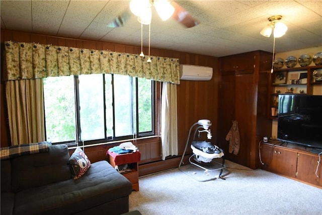 living area featuring a wall mounted AC, a ceiling fan, wood walls, and light colored carpet