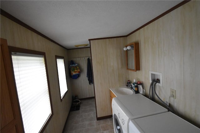 clothes washing area featuring crown molding, laundry area, a sink, baseboards, and washing machine and dryer