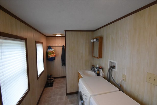 laundry area with crown molding, wooden walls, laundry area, baseboards, and washing machine and dryer