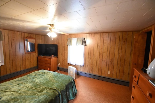 bedroom featuring wood walls, a ceiling fan, a baseboard heating unit, and carpet flooring