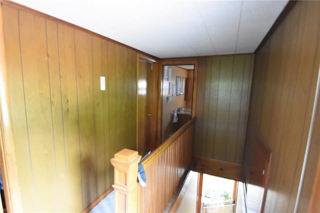 hall with wood walls and an upstairs landing