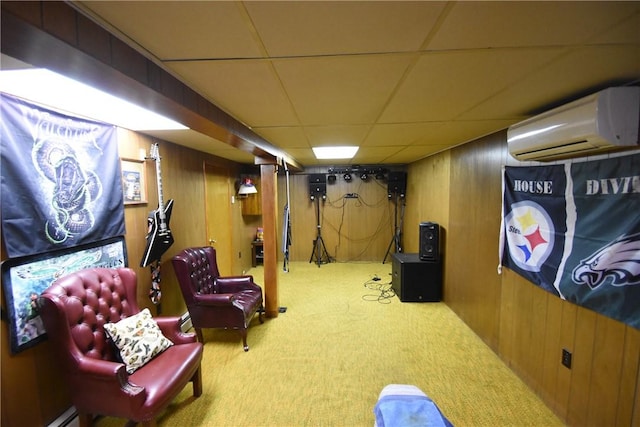 finished below grade area featuring carpet floors, a drop ceiling, wooden walls, baseboard heating, and a wall unit AC
