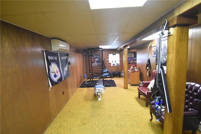 exercise area with carpet, wood walls, a wall mounted air conditioner, and a paneled ceiling