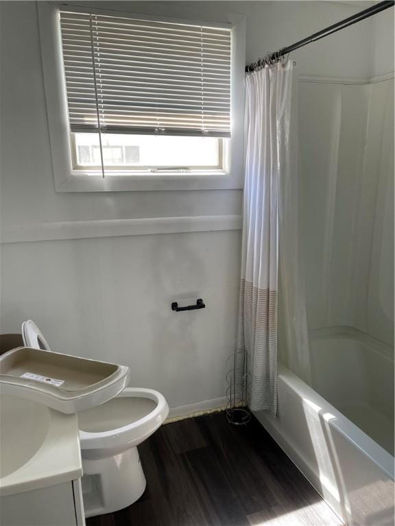 bathroom with toilet, a wealth of natural light, shower / tub combo, and wood finished floors