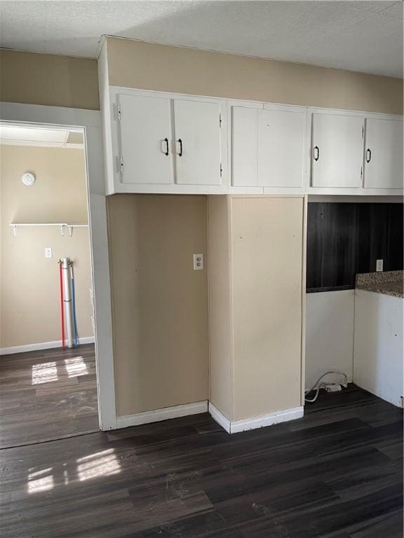 kitchen featuring dark wood-type flooring, white cabinetry, and baseboards