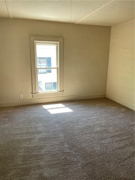 spare room featuring carpet flooring and baseboards