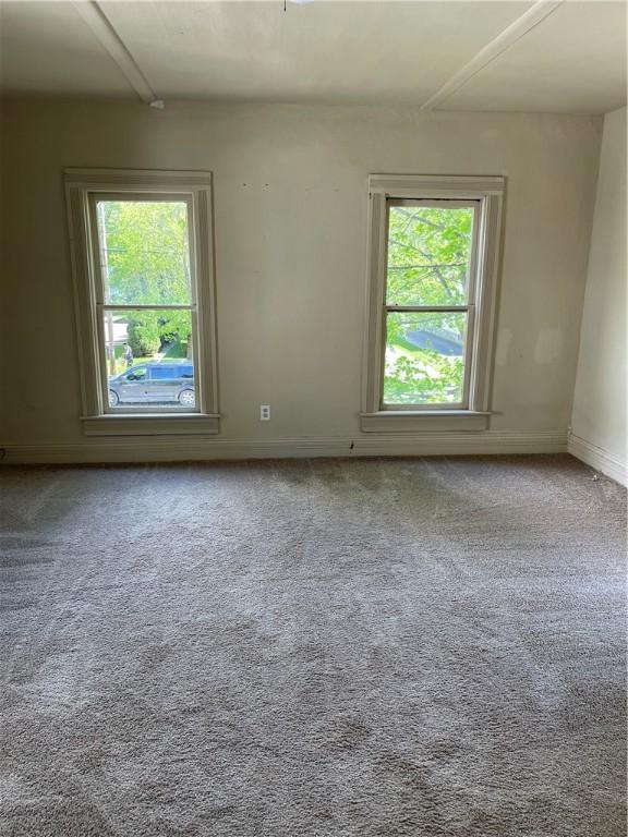 empty room featuring carpet floors and baseboards