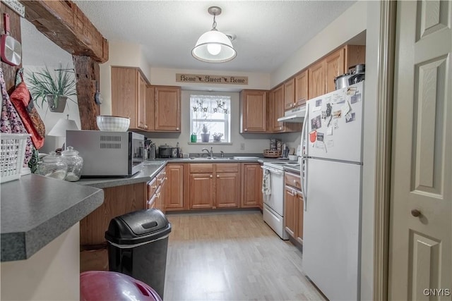 kitchen with white appliances, a kitchen bar, under cabinet range hood, a sink, and light wood finished floors