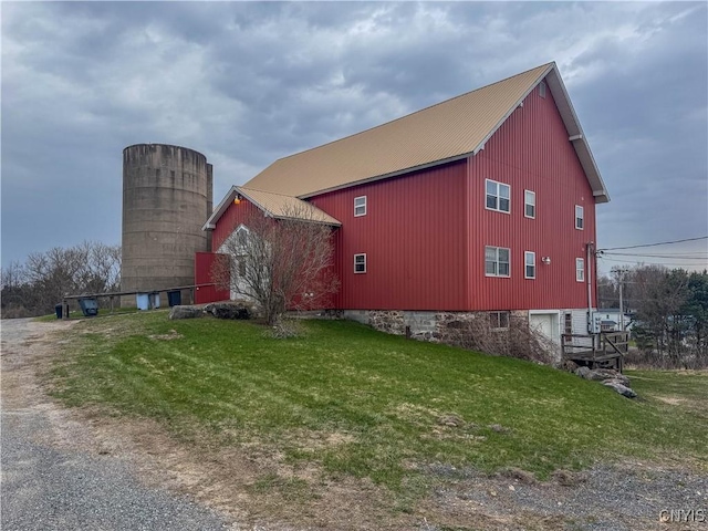 view of side of property featuring a lawn, driveway, and metal roof