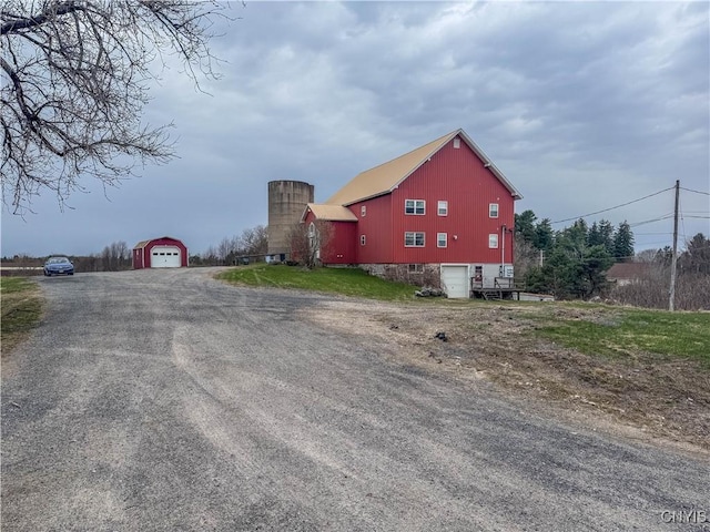 view of side of home featuring a detached garage, driveway, and an outbuilding