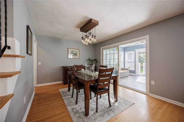 dining room with an inviting chandelier, baseboards, and light wood-type flooring