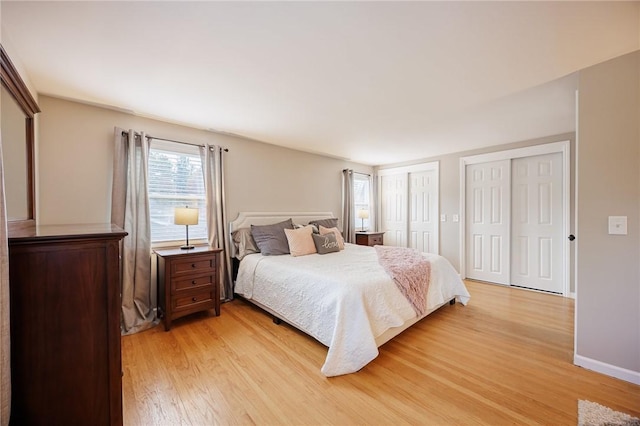 bedroom featuring baseboards, light wood-style flooring, and multiple closets