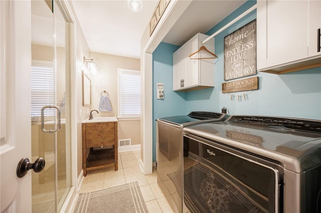 washroom with visible vents, a sink, cabinet space, independent washer and dryer, and light tile patterned floors