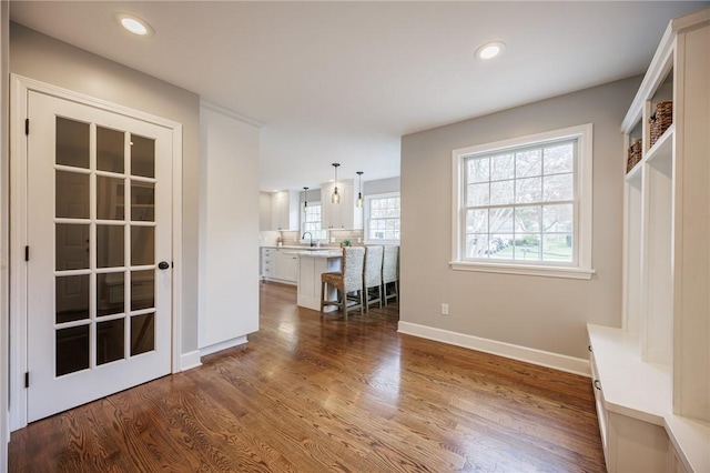 interior space with a sink, baseboards, recessed lighting, and dark wood finished floors