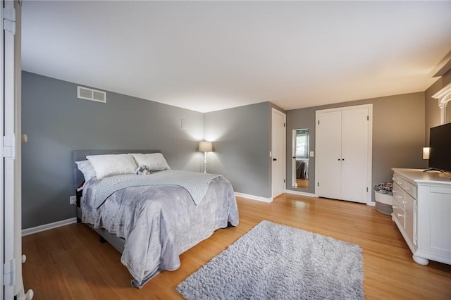 bedroom with visible vents, light wood-style floors, and baseboards