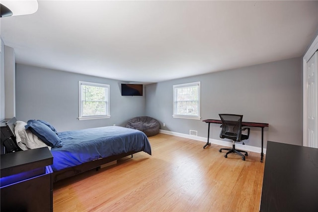 bedroom featuring baseboards, multiple windows, light wood finished floors, and visible vents