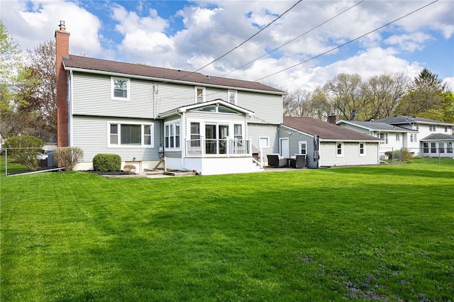 back of property featuring a lawn, fence, a chimney, and a sunroom