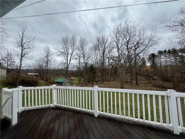 wooden deck with a storage unit, a yard, and an outbuilding