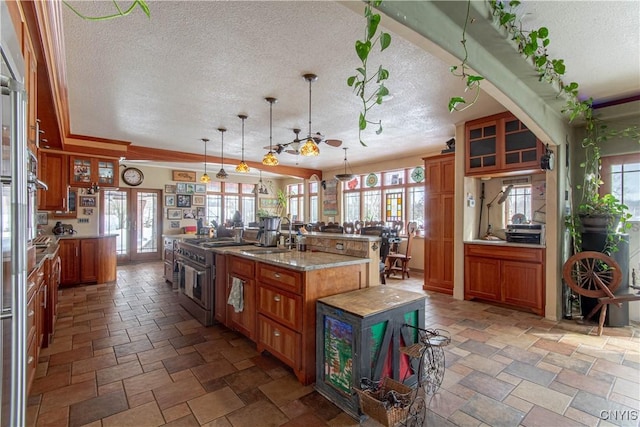 kitchen with brown cabinetry, a large island with sink, and a textured ceiling