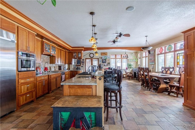 kitchen featuring a sink, stainless steel appliances, brown cabinets, and a textured ceiling