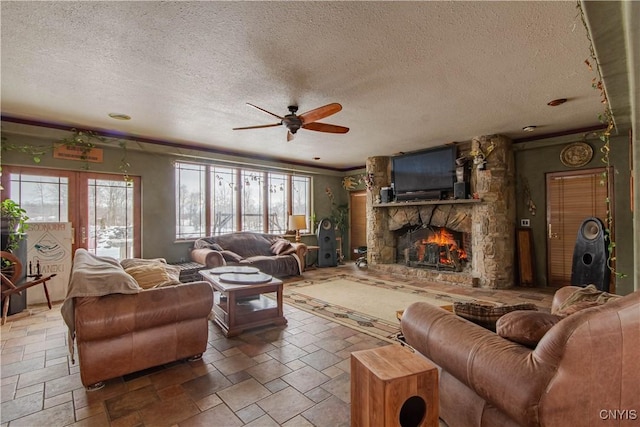 living area with a textured ceiling, ceiling fan, stone tile flooring, and a fireplace