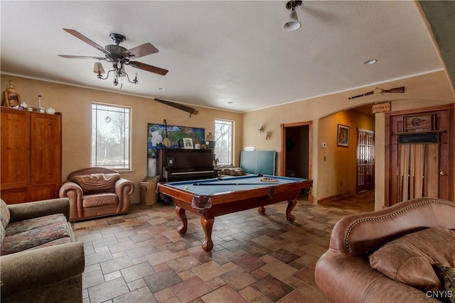 rec room with stone finish floor, ceiling fan, arched walkways, and pool table