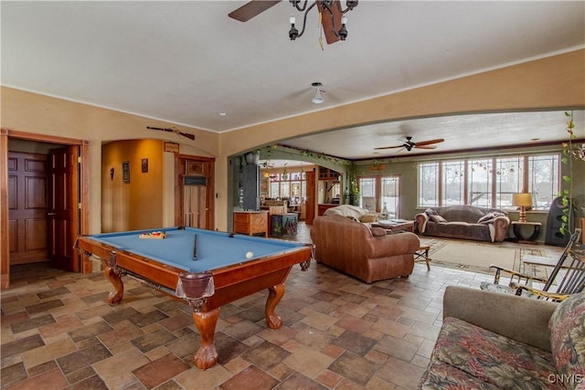 rec room with arched walkways, ceiling fan, billiards, and stone tile flooring