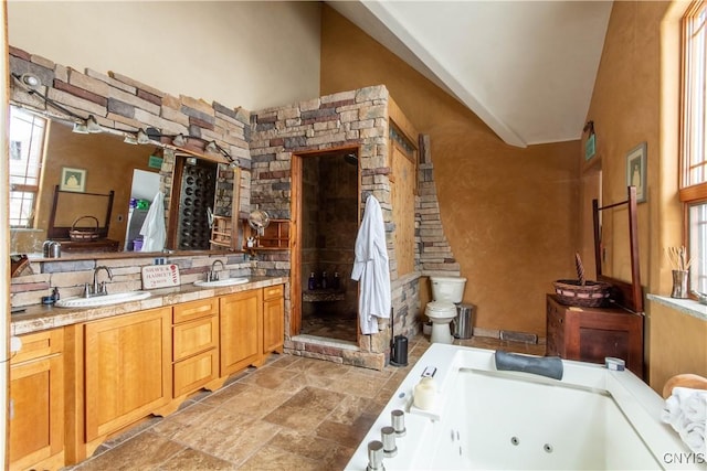 full bathroom with double vanity, stone finish floor, a tub with jets, and a sink