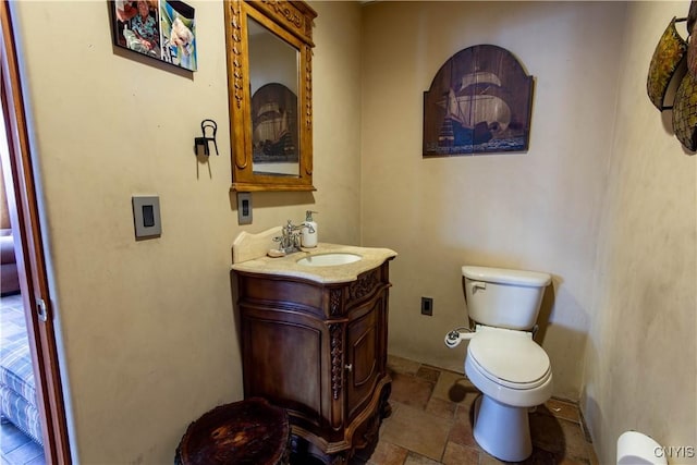 bathroom with vanity, toilet, and stone tile flooring
