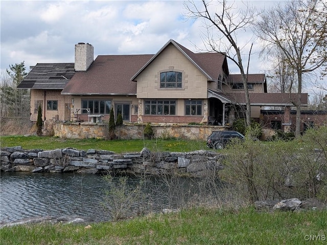 rear view of property featuring a chimney and a shingled roof