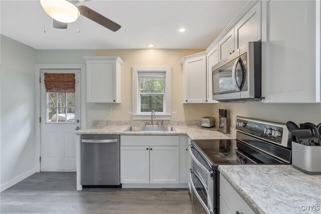 216 Harry Bryant Rd, Amboy, NY 13493 - kitchen with stainless steel appliances, a sink, light wood finished floors, white cabinets, and recessed lighting