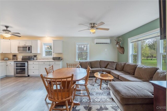 216 Harry Bryant Rd, Amboy, NY 13493 - living room featuring a wall mounted AC, a ceiling fan, and light wood-style floors