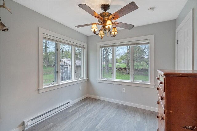 216 Harry Bryant Rd, Amboy, NY 13493 - unfurnished dining area featuring a baseboard heating unit, light wood-style floors, ceiling fan, and baseboards