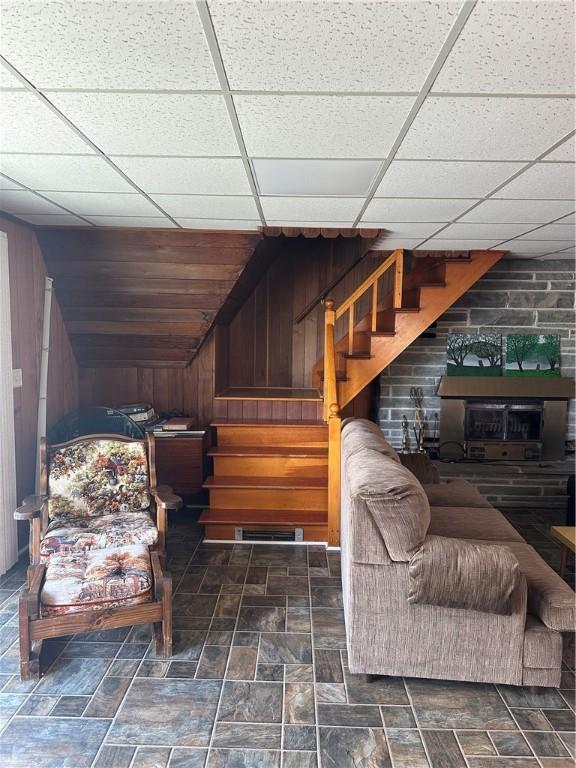 living area featuring wooden walls, visible vents, stone finish flooring, and stairway