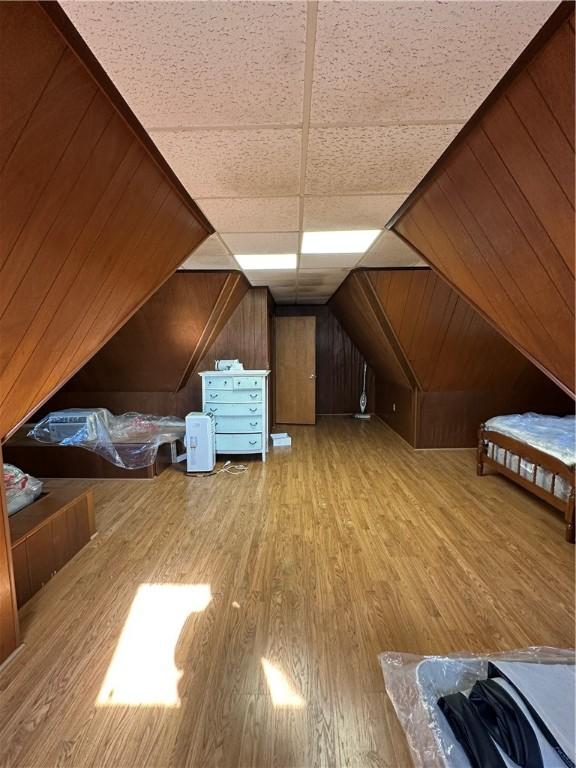 additional living space with wooden walls, vaulted ceiling, and wood finished floors