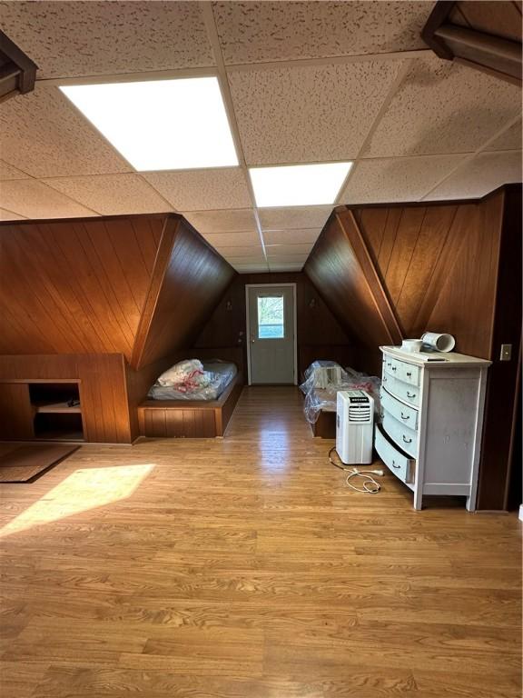 additional living space with wood walls, wood finished floors, and vaulted ceiling