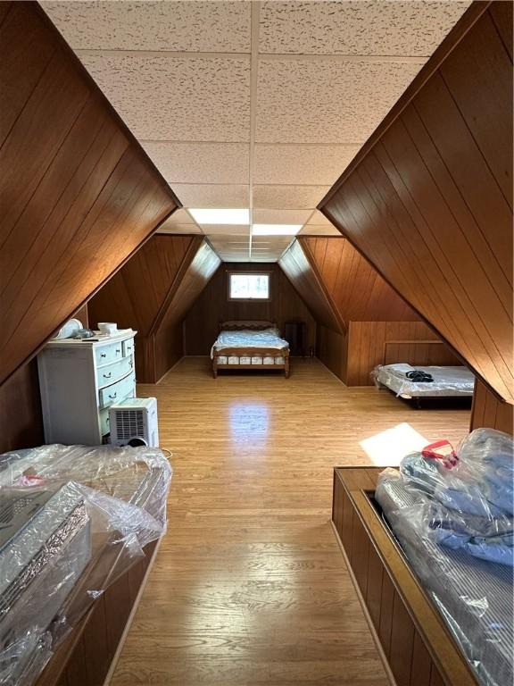 bonus room featuring wood walls, lofted ceiling, and light wood-style floors