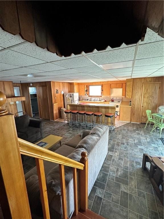 living room with wood walls and a drop ceiling