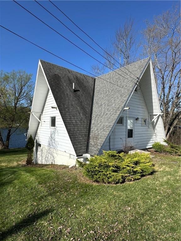 view of side of home with roof with shingles and a lawn