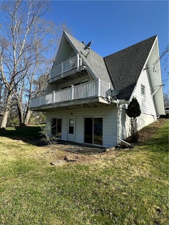 back of house with roof with shingles, a patio, a yard, and a balcony