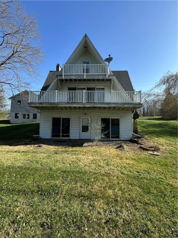 back of house featuring a lawn, a chimney, and a balcony