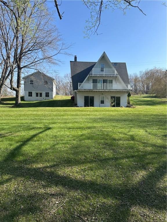 back of property featuring a lawn, a chimney, and a balcony