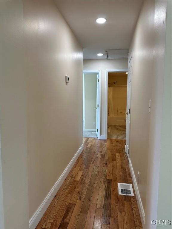 hallway featuring baseboards, recessed lighting, hardwood / wood-style floors, and visible vents