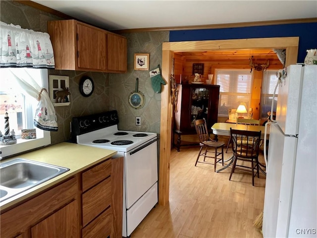 23183 Kitto Marina Dr, Brownville, NY 13634 - kitchen with ornamental molding, white appliances, light countertops, brown cabinets, and light wood-style flooring