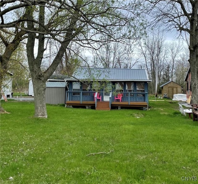 23183 Kitto Marina Dr, Brownville, NY 13634 - rear view of property featuring a yard, a deck, an outbuilding, and metal roof