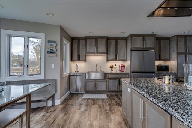 25524 County Route 57, Lyme, NY 13693 - kitchen with wood finished floors, baseboards, a sink, stone counters, and appliances with stainless steel finishes