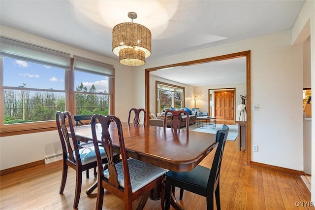 dining area with a chandelier, light wood-style floors, and baseboards