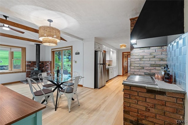 2380 E Lake Rd, Spafford, NY 13152 - dining room featuring a wood stove, light wood finished floors, baseboards, healthy amount of natural light, and beamed ceiling