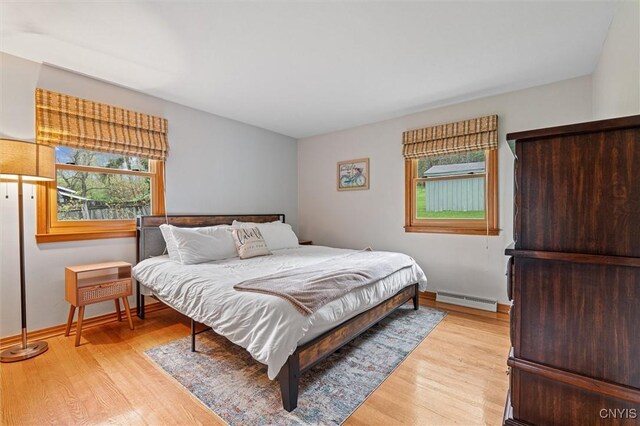 2380 E Lake Rd, Spafford, NY 13152 - bedroom with a baseboard radiator, multiple windows, and light wood finished floors