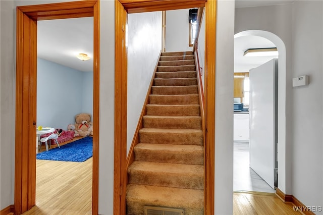 stairway with visible vents, arched walkways, and wood finished floors